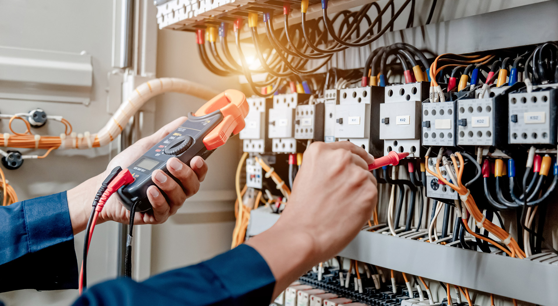 man plugging wires into an electrical power panel